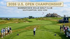 Golfer tees off on a coastal green as spectators watch; banner reads '2026 U.S. OPEN CHAMPIONSHIP' above a clubhouse.
