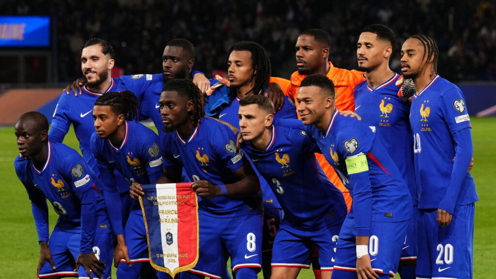 France national soccer team players in blue, posing together on the field after a win, holding a banner that reads France Ukraine 2025.