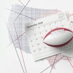 September 2026 calendar with an American football resting on a schedule page against a dotted world-map background.